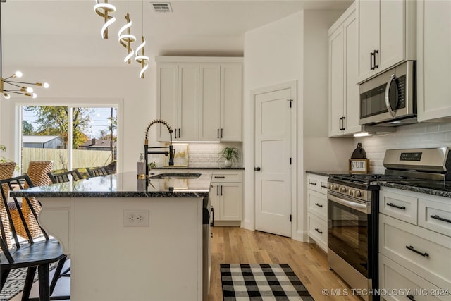 kitchen featuring backsplash, stainless steel appliances, a kitchen island with sink, and sink