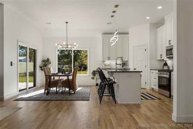 kitchen featuring white cabinetry, a breakfast bar, hanging light fixtures, and appliances with stainless steel finishes