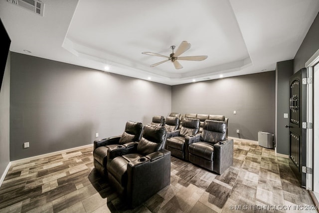 cinema room featuring a tray ceiling, ceiling fan, and hardwood / wood-style flooring