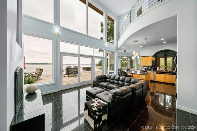 tiled living room with a water view, a towering ceiling, and a wealth of natural light