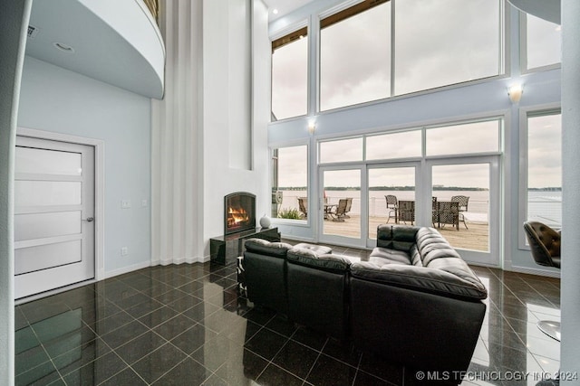 living room featuring a water view, a towering ceiling, and a fireplace