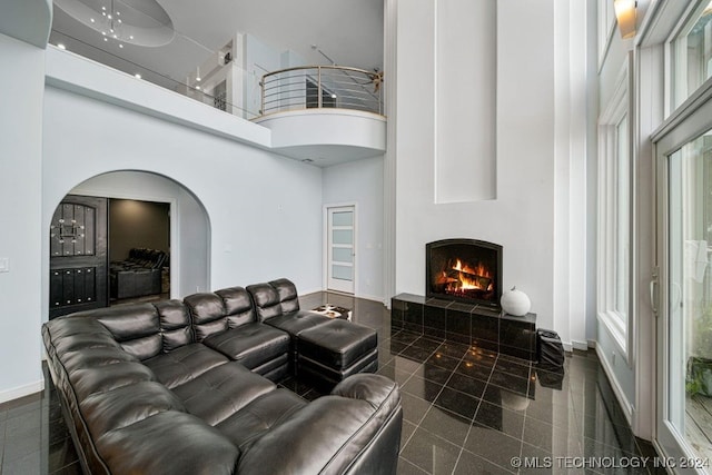 living room with a tile fireplace and a high ceiling