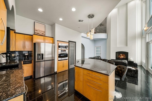 kitchen with pendant lighting, stainless steel appliances, tasteful backsplash, and dark stone counters