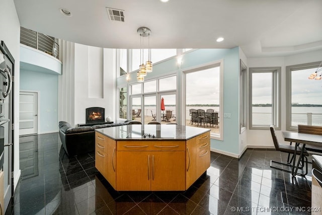 kitchen with a water view, a kitchen island, and hanging light fixtures