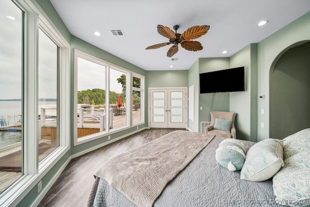 bedroom featuring hardwood / wood-style floors, french doors, a water view, and ceiling fan