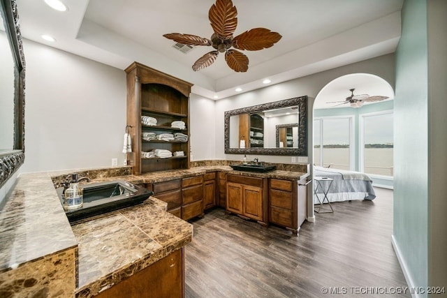 bathroom featuring a raised ceiling, vanity, a water view, and wood-type flooring