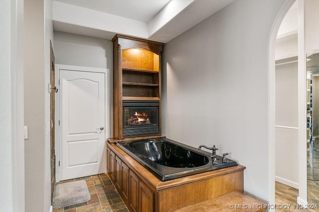 bathroom featuring a tub and a large fireplace