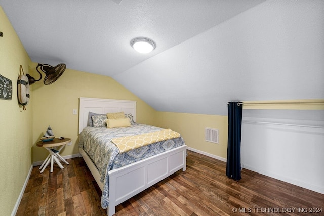 bedroom featuring a textured ceiling, dark hardwood / wood-style flooring, and vaulted ceiling