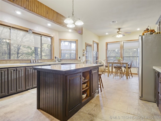 kitchen featuring a wealth of natural light, a center island, dark brown cabinets, and stainless steel refrigerator