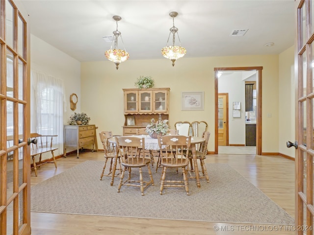 dining room with a notable chandelier, light wood-type flooring, and french doors