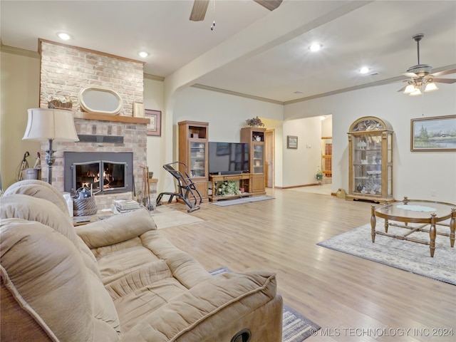 living room featuring ceiling fan, light hardwood / wood-style floors, crown molding, and a fireplace