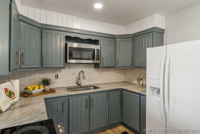 kitchen featuring decorative backsplash, sink, gray cabinets, light hardwood / wood-style floors, and white fridge with ice dispenser