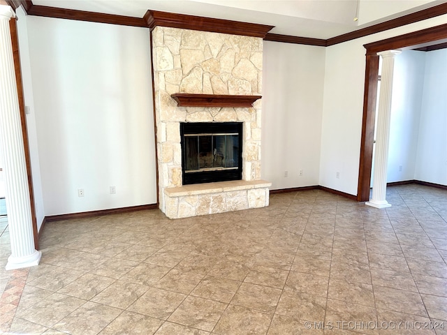 unfurnished living room featuring a stone fireplace, ornate columns, and ornamental molding