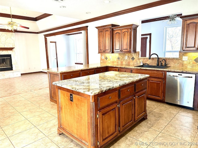 kitchen with dishwasher, a stone fireplace, sink, ornamental molding, and a kitchen island