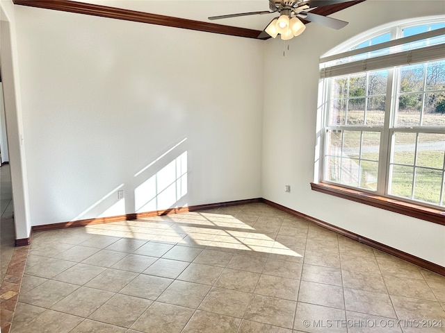 empty room with ceiling fan, light tile patterned floors, and crown molding