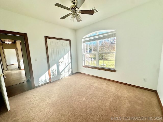 unfurnished bedroom with light carpet, a closet, and ceiling fan