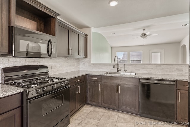 kitchen featuring black appliances, light stone counters, sink, and tasteful backsplash