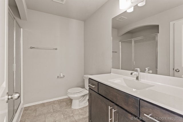 bathroom with toilet, vanity, tile patterned floors, and a shower with door