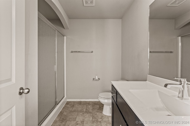 bathroom with vanity, a shower with shower door, and toilet