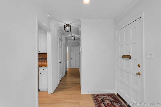 hallway with light wood-type flooring and ornamental molding