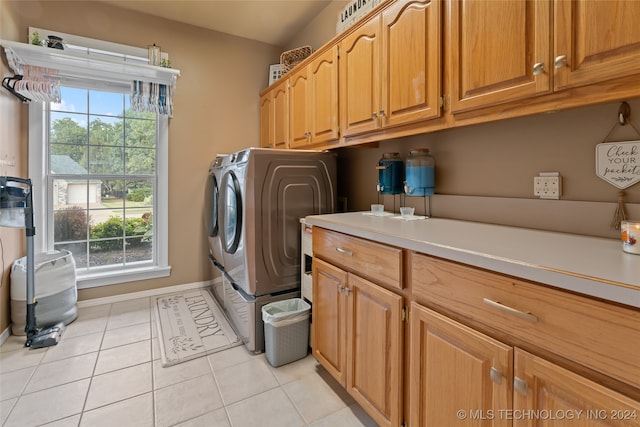 clothes washing area featuring washer and dryer, cabinets, and light tile patterned floors