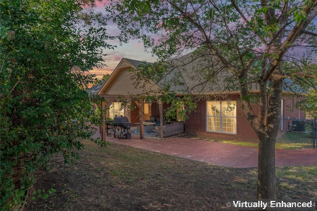 back house at dusk featuring a patio