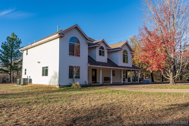 front of property with central AC unit, covered porch, and a front yard