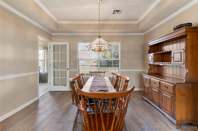 dining room with a raised ceiling, a wealth of natural light, and hardwood / wood-style floors