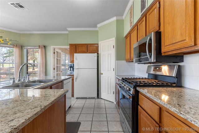 kitchen featuring light stone countertops, appliances with stainless steel finishes, tasteful backsplash, ornamental molding, and sink