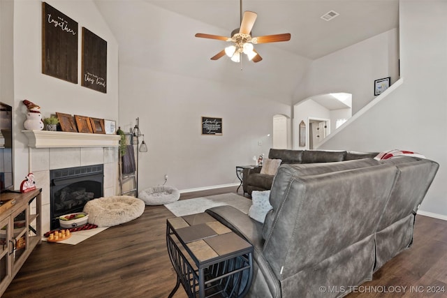 living room with dark hardwood / wood-style floors, ceiling fan, a tile fireplace, and vaulted ceiling