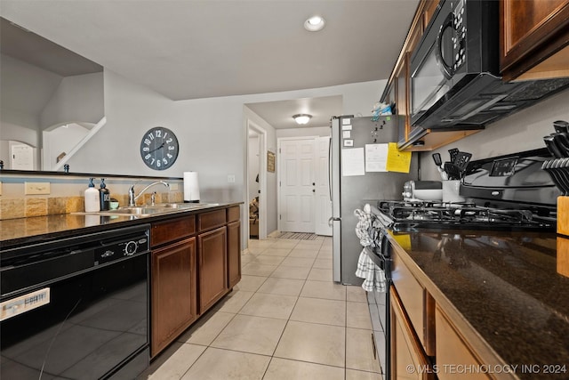 kitchen with black appliances, light tile patterned flooring, dark stone countertops, and sink