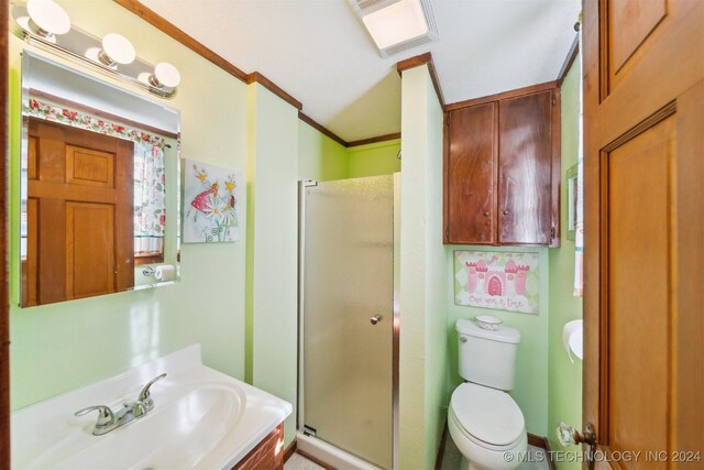 bathroom featuring crown molding, toilet, vanity, and a shower with shower door