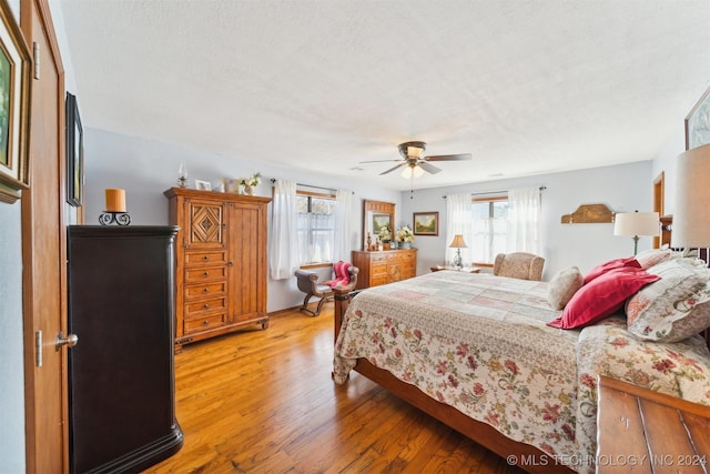 bedroom with hardwood / wood-style flooring, ceiling fan, and a textured ceiling