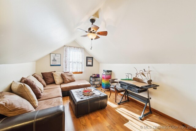 living room with hardwood / wood-style flooring, ceiling fan, and vaulted ceiling