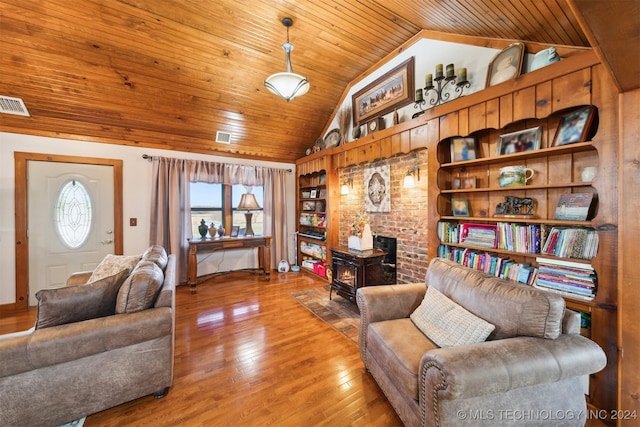 living room with built in shelves, vaulted ceiling, a wood stove, and hardwood / wood-style flooring