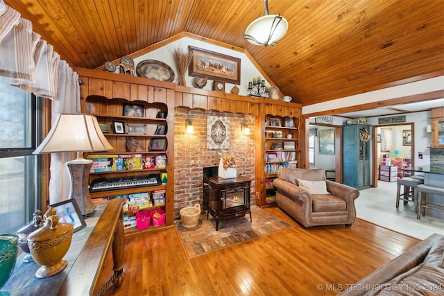 living room with built in shelves, lofted ceiling, hardwood / wood-style floors, and a wood stove