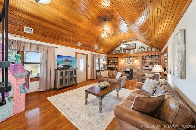 living room featuring a wood stove, wood-type flooring, built in features, and vaulted ceiling