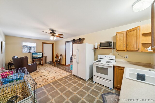 kitchen with ceiling fan, white appliances, a barn door, and sink