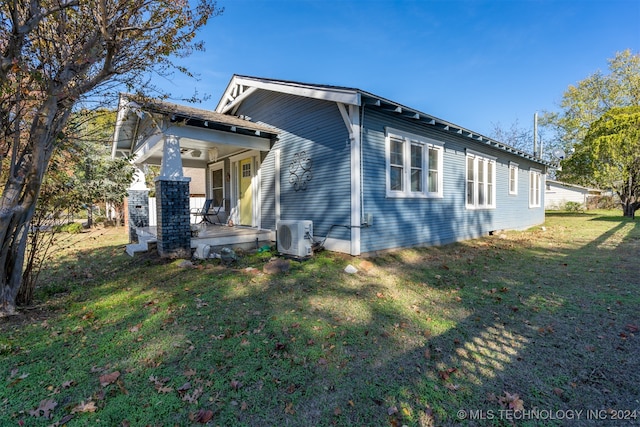 view of side of home with a lawn, ac unit, and covered porch