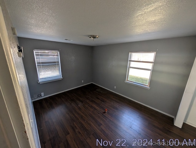 spare room featuring dark hardwood / wood-style flooring and a textured ceiling