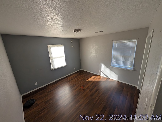 empty room featuring a textured ceiling and dark hardwood / wood-style flooring