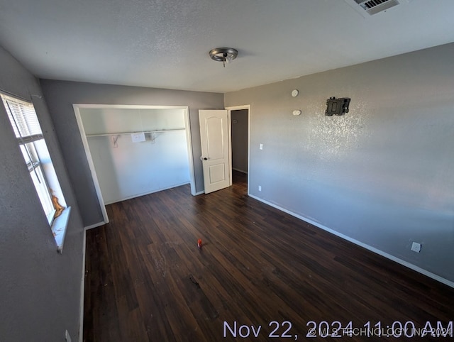 unfurnished bedroom featuring dark wood-type flooring and a closet