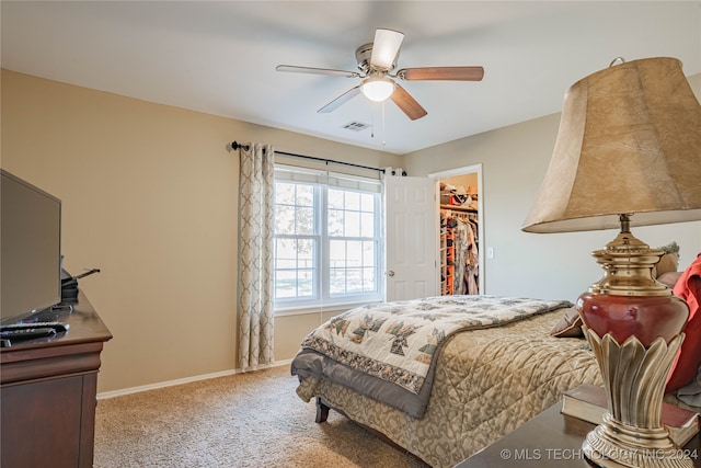 carpeted bedroom featuring a walk in closet, a closet, and ceiling fan