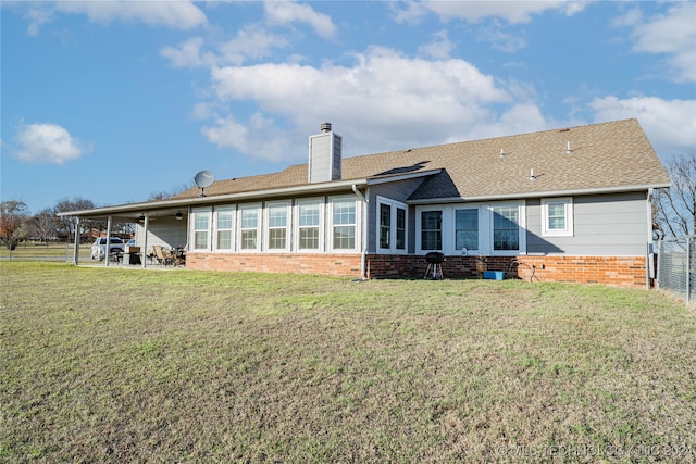 rear view of property featuring a sunroom and a lawn