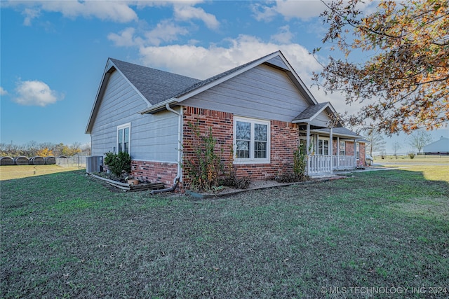 view of front of home featuring a porch, a front yard, and central AC