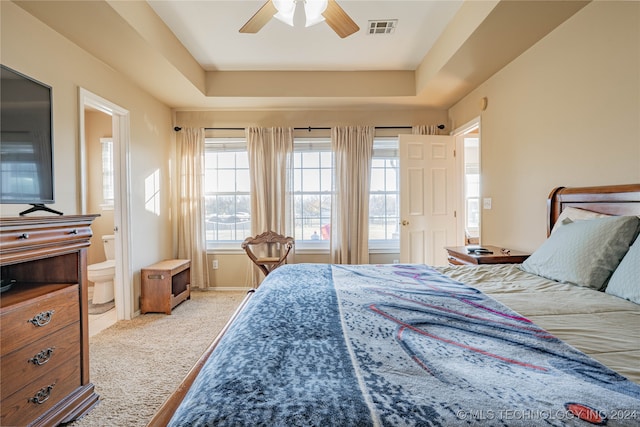 carpeted bedroom with connected bathroom, a raised ceiling, and ceiling fan