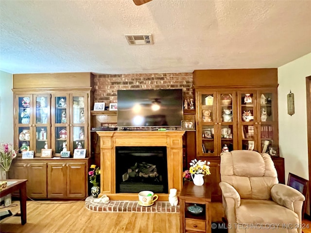 living room with a textured ceiling, light hardwood / wood-style floors, and a fireplace