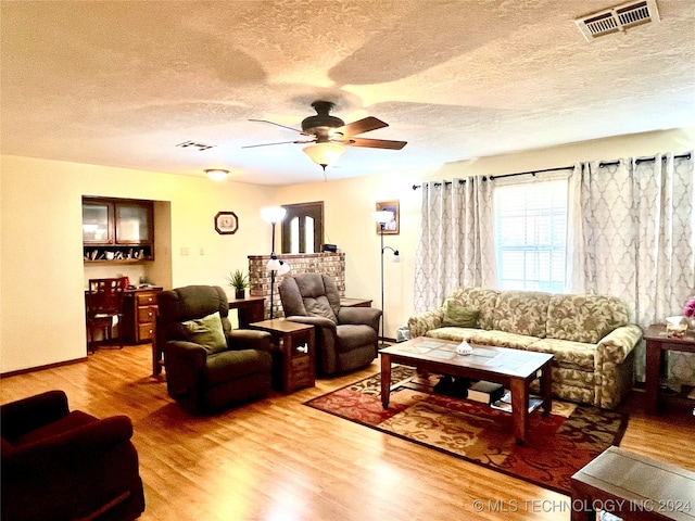 living room with ceiling fan, wood-type flooring, and a textured ceiling