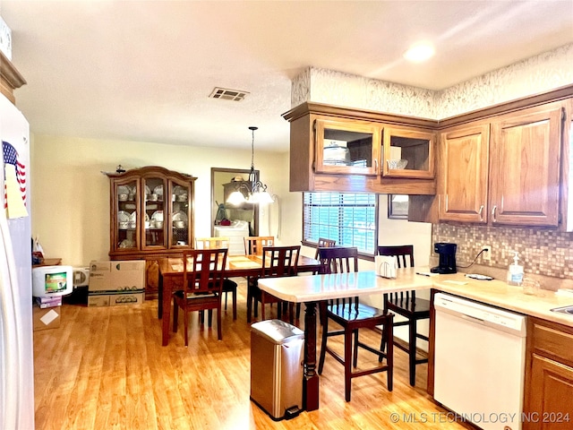 kitchen with dishwasher, light wood-type flooring, hanging light fixtures, and an inviting chandelier