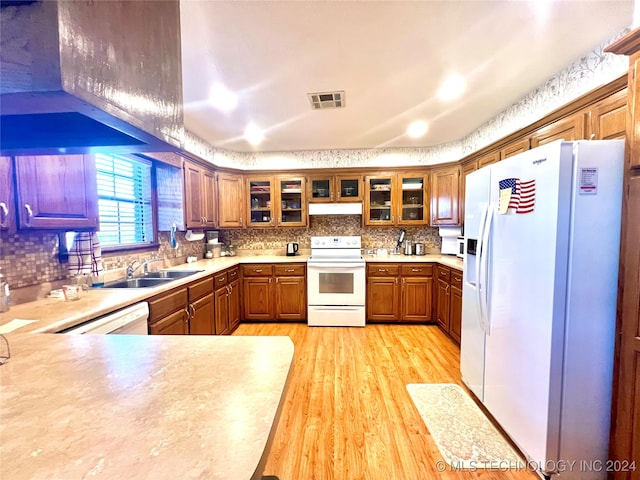 kitchen with sink, light hardwood / wood-style flooring, kitchen peninsula, white appliances, and decorative backsplash